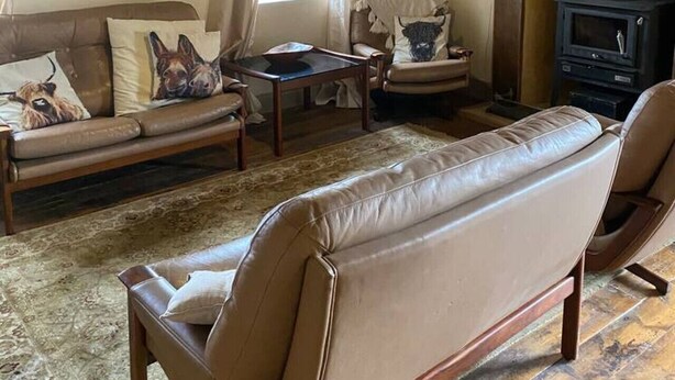 Una sala de estar acogedora con un sofá, sillones, una mesita y una chimenea.