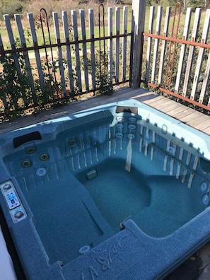 A hot tub with a control panel, surrounded by a wooden fence.