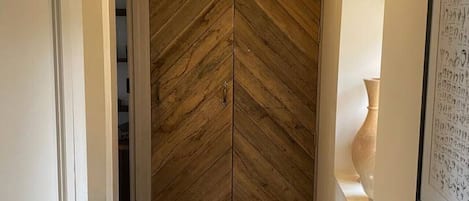 Un pasillo con suelo de parqué tipo espiga y una puerta con un diseño similar.