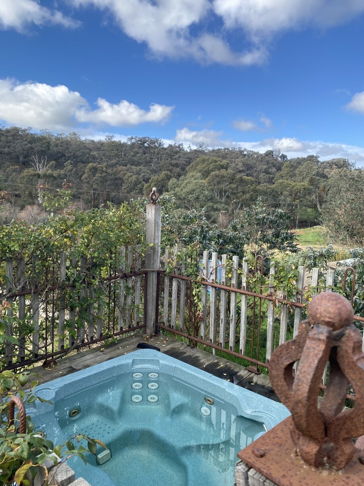 A hot tub with a wooden fence and a view of a forested hill.