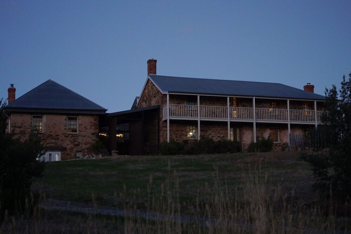A two-story stone building with a balcony and a separate wing.