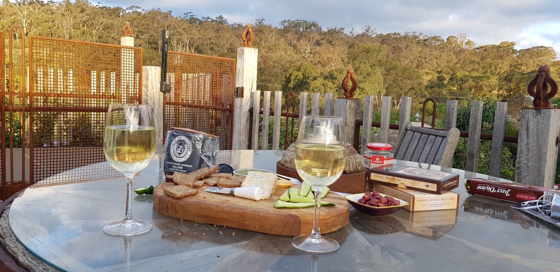 A table set with wine glasses, cheese, crackers, and a box of chocolates.