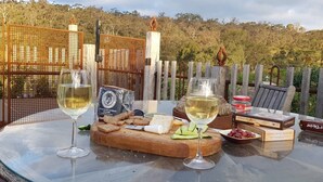 Una mesa dispuesta con copas de vino, queso, galletas y una caja de bombones.