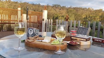 A table set with wine glasses, cheese, crackers, and a box of chocolates.