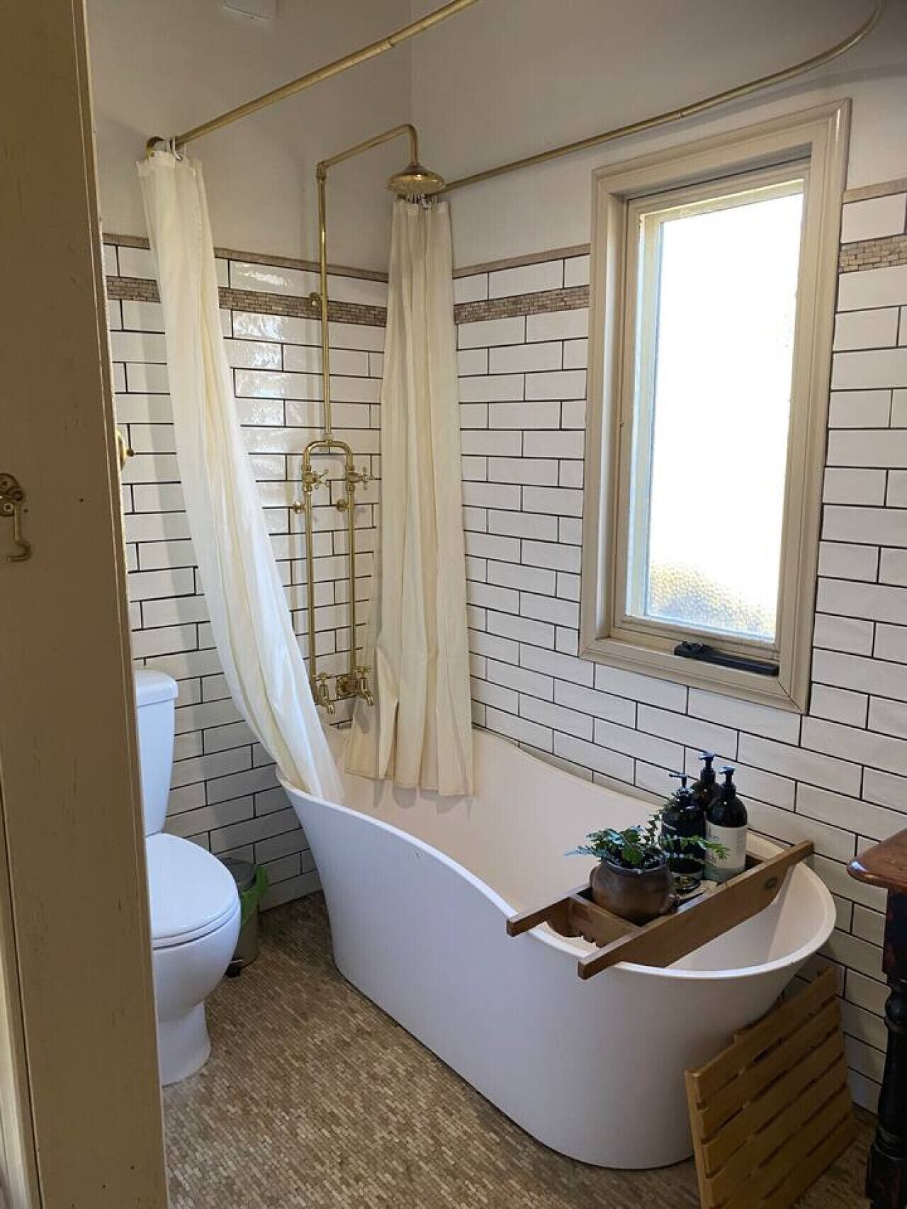 A bathroom with a freestanding bathtub, a toilet, and a window.