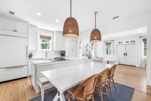 A spacious kitchen with white cabinetry, a central island, and two hanging pendant lights. - Amos Cottage in Rosemary Beach - bikes, pools, and much more! (Inlet Beach)