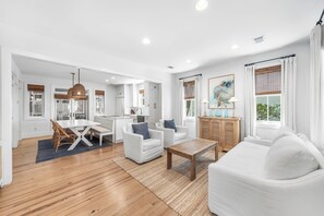 A spacious living area with a dining table, white sofas, and a wooden coffee table. - Amos Cottage in Rosemary Beach - bikes, pools, and much more! (Inlet Beach)