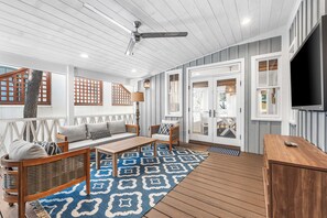 A spacious outdoor area with a ceiling fan, wooden deck, and a seating area with a sofa and chairs. - Amos Cottage in Rosemary Beach - bikes, pools, and much more! (Inlet Beach)