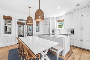 A modern kitchen with white cabinetry, a central island, and pendant lighting. - Amos Cottage in Rosemary Beach - bikes, pools, and much more! (Inlet Beach)