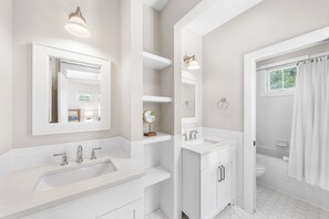 Un baño moderno con un espejo grande, dos lavamanos y una zona de ducha.