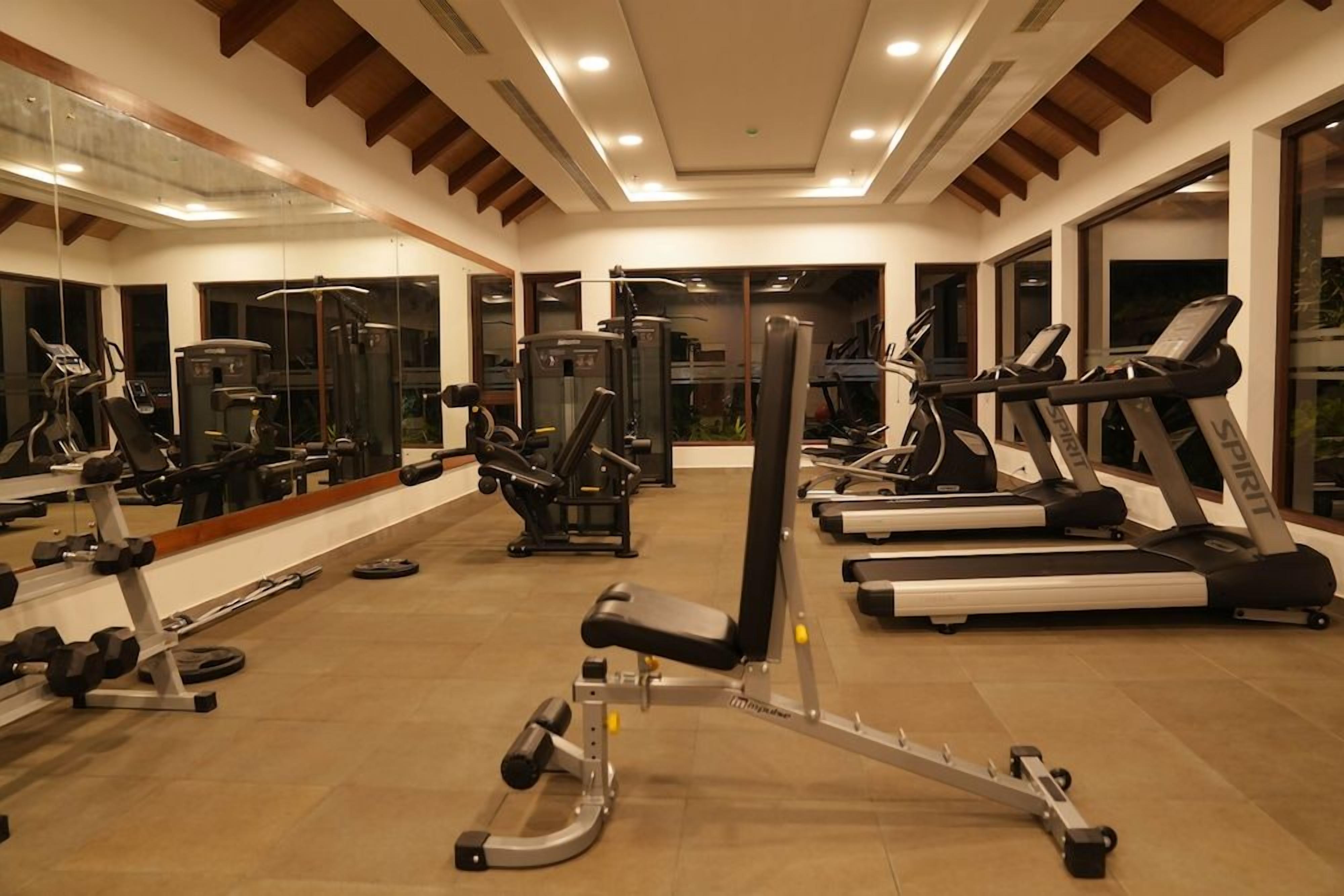 A gym with various exercise equipment including treadmills, weight machines, and free weights.