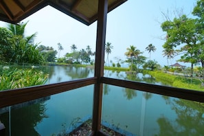 A view through a window with a reflection of palm trees and a body of water. - Gokulam Grand Resort and Spa Kumarakom (Kottayam)