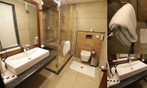A bathroom with two sinks, a glass shower enclosure, a toilet, and a towel rack. - Gokulam Grand Resort and Spa Kumarakom (Kottayam)