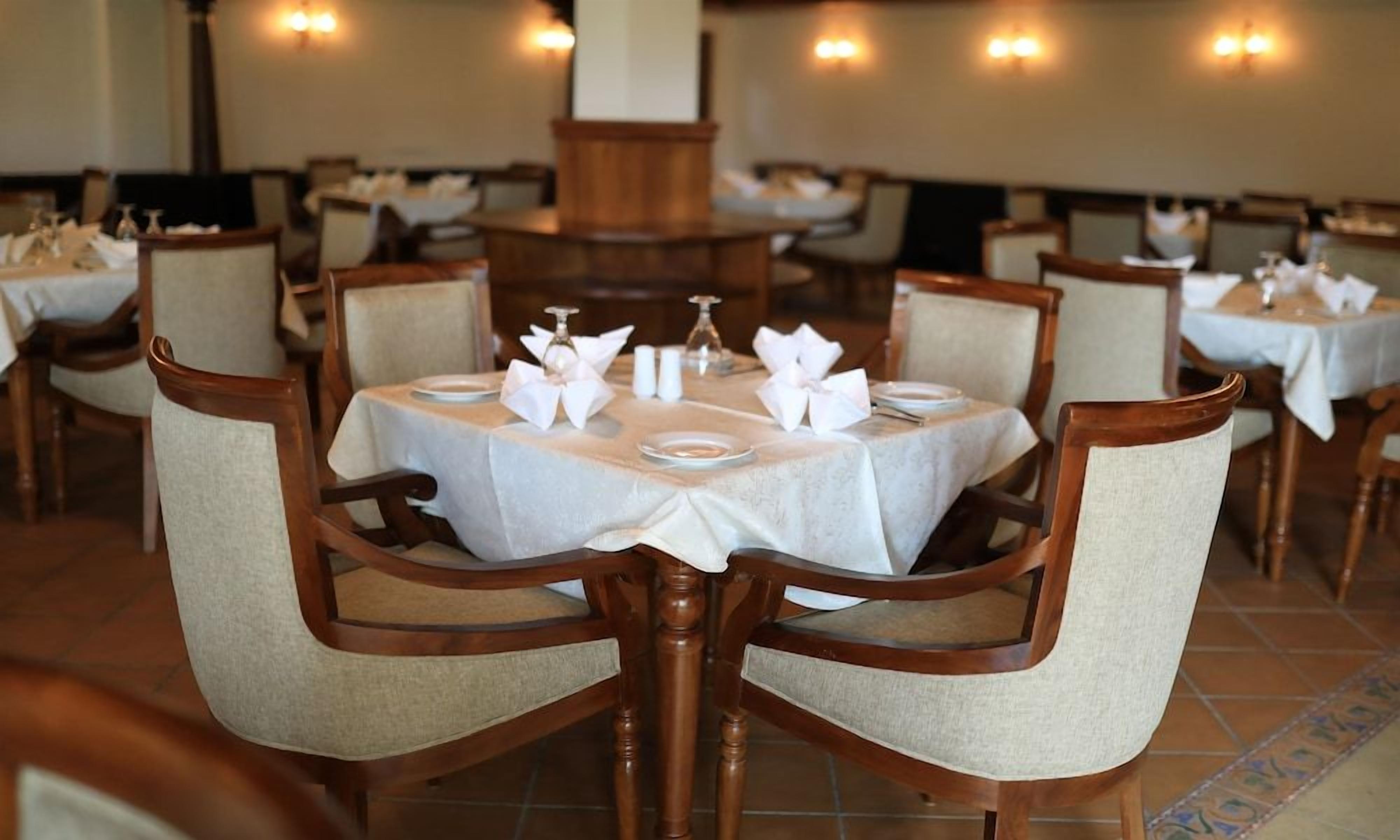 A dining area with round tables, chairs, and table settings.
