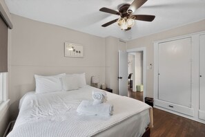 A bedroom with a bed, a ceiling fan, a door, and a framed picture on the wall. - Cozy Private 1-BR Upper Unit with Kitchen - 5111B (Tampa)