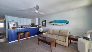 A compact living space with a kitchenette, a sofa, a coffee table, and a fan.