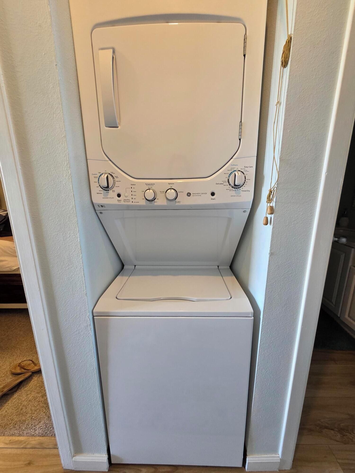 A compact washer and dryer unit installed in a narrow space, likely a laundry room.