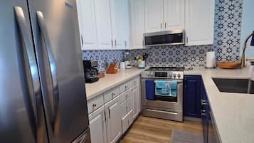 Una cucina moderna con elettrodomestici in acciaio inossidabile, mobili bianchi e uno schienale decorato.