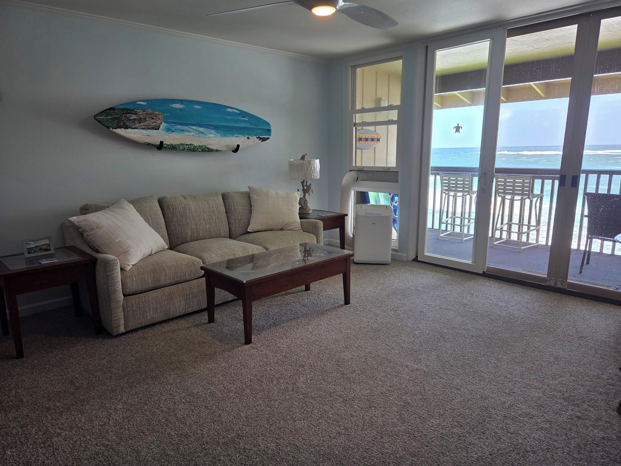A living room with a sofa, a coffee table, and a large window with a view of the ocean.