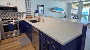 A modern kitchen with a central island, stainless steel appliances, and a patterned backsplash.