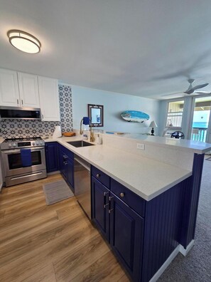 A modern kitchen with a central island, stainless steel appliances, and a patterned backsplash.