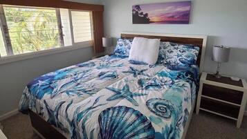 A bedroom with a bed, a ceiling fan, a nightstand, a lamp, and a painting on the wall.