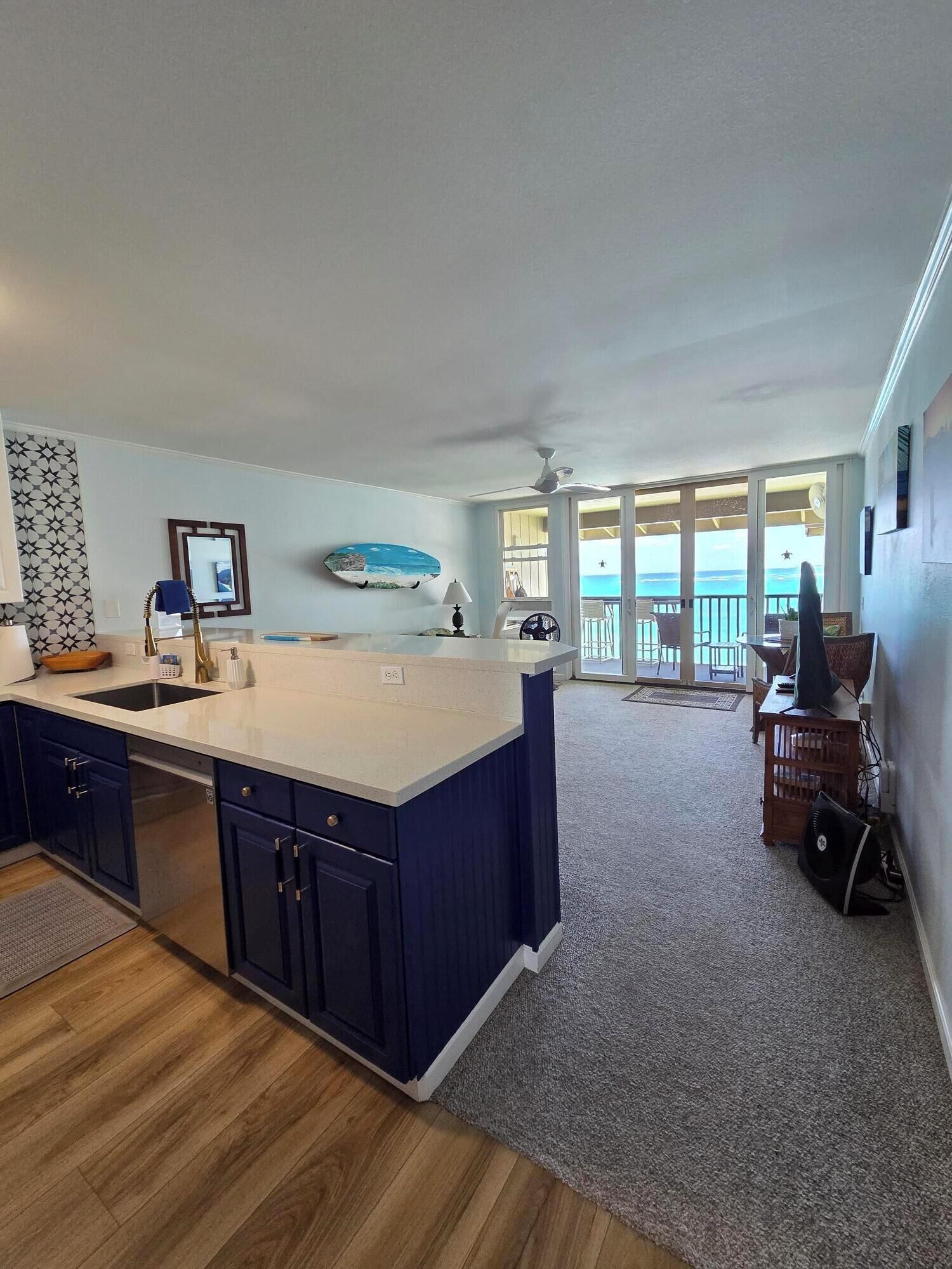 A kitchen with a large island, a dining area with a view, and a ceiling fan.