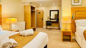 Habitación de hotel con dos camas, un escritorio, una silla, un armario y baño.