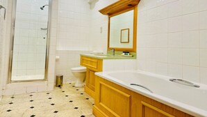 Un baño con ducha, inodoro, tocador y un espejo grande.
