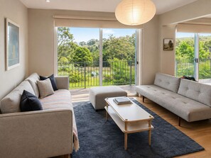 A modern living room with two sofas, a coffee table, and a view of a balcony with greenery. - Moonrise by Ready Set Stay (Harcourt North)