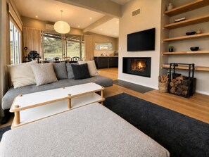A modern living room with a sofa, a coffee table, a fireplace, and a TV mounted on the wall.