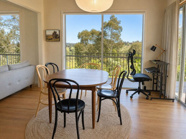 A dining area with a round table, chairs, and a view of the outdoors.