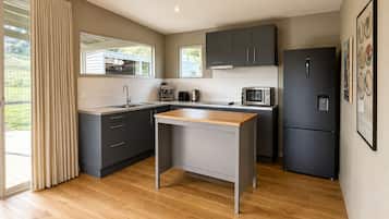 A modern kitchen with a central island, dark cabinetry, and a stainless steel refrigerator.