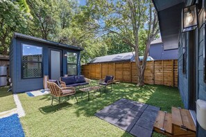 A backyard with a small blue structure, outdoor furniture, and a wooden fence.
