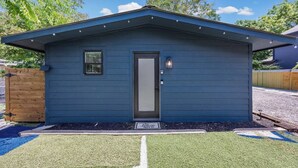 Un pequeño edificio de una sola planta con fachada azul oscuro, una puerta principal, un ventanal y un buzón.