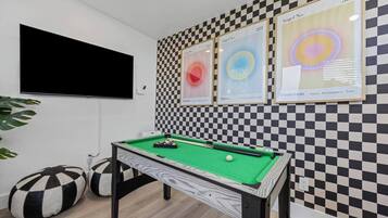 Una mesa de billar con pared a cuadros y obras de arte enmarcadas.