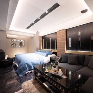 Una habitación de hotel moderna con una cama, un sofá, una mesa de centro de vidrio y un minibar.