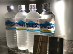 Four bottles of water with labels, placed on a reflective surface.