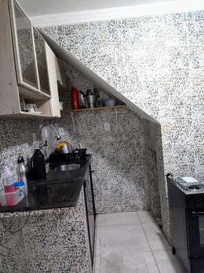 A kitchen with a tiled backsplash, a stove, and a sink.