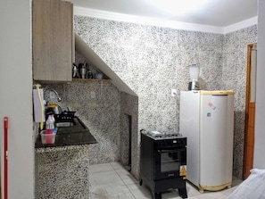 Una cucina compatta con piano cottura integrato, un piccolo frigorifero e un forno a microonde.