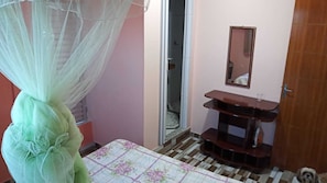 Una stanza con un letto, un comodino, uno specchio e una porta.