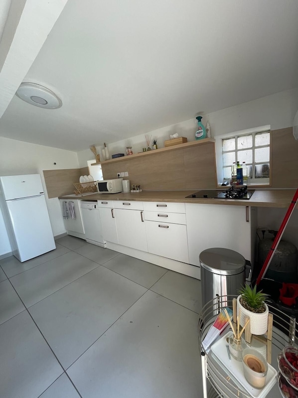 A modern kitchen with white cabinets, a built-in oven, and a window with blinds.