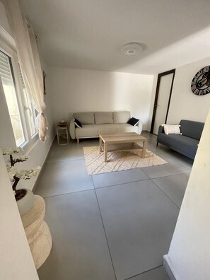 A living room with a sofa, a coffee table, a small side table, and a potted plant. - Vrbo Property (Berre-l'Étang)