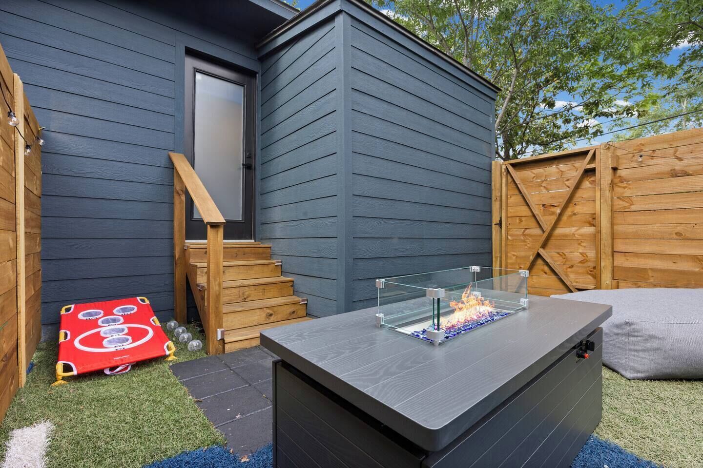 A patio area with a glass table and a fire feature, surrounded by wooden steps and a door.