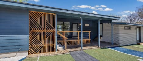 A modern building with a covered porch, a wooden fence, and a well-maintained lawn.