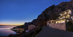 Ein Küsteneigentum mit einem gepflasterten Weg, einer Steinmauer und einem Gebäude mit Balkonen mit Blick auf das Meer.