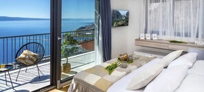 Ein Balkon mit Meerblick, ein Bett mit Ausblick und ein kleiner Tisch mit Stuhl.