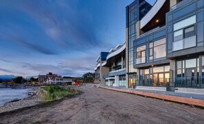 Een modern gebouw met een golvende gevel, grote ramen en uitzicht op het water.