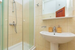 A bathroom with a glass-enclosed shower, a white sink, and a wooden medicine cabinet. - Hedera Estate, Hedera A1 (Dubrovnik)