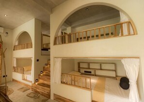 A room with bunk beds, wooden railings, and a staircase.